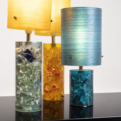 three different colored glass lamps on a table