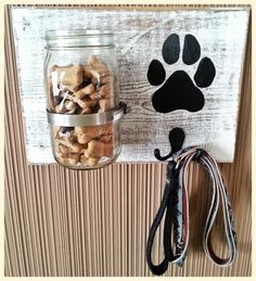 a mason jar filled with dog treats next to a leash holder on a wooden wall