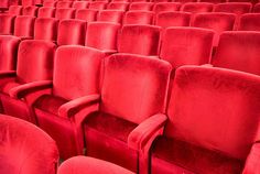 rows of red velvet seats in an empty theater or movie theatre, viewed from the front row