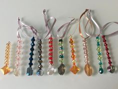 six different colored beads are lined up on a white surface and tied together with ribbons