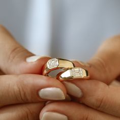 two hands holding gold rings with diamonds on them