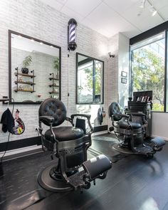 a salon with black chairs and mirrors on the wall, in front of large windows