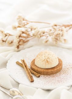 a small dessert on a white plate with cinnamon sticks