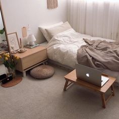 a laptop computer sitting on top of a bed in a bedroom next to a window