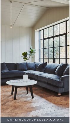 a living room with a large sectional couch and coffee table in front of the window