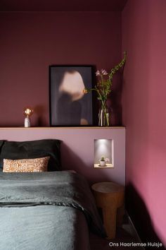 a bedroom with pink walls and green bedding, two side tables on either side