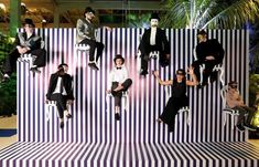 a group of people sitting on top of a white and black striped wall