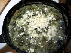 a pan filled with spinach and cheese on top of a stove