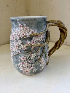 a ceramic mug with branches and flowers painted on the inside, sitting on a table