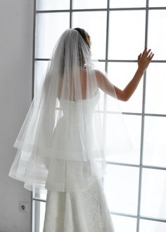 the back of a bride's veil as she stands in front of a window