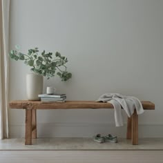 a wooden bench sitting in front of a window next to a potted plant and pair of shoes