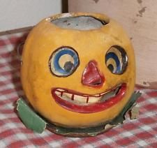 a yellow pumpkin with blue eyes and mouth on a checkered tablecloth covered surface