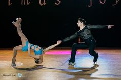 two people are performing on a stage with one holding the other's leg in the air