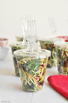 several plastic cups filled with salad and forks