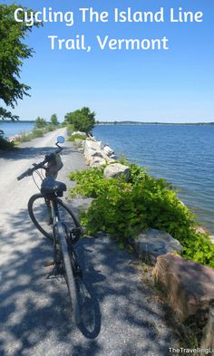 a bike parked on the side of a dirt road next to a body of water