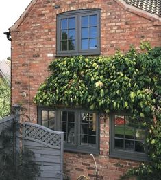 a brick house with green vines growing on it's side and a bicycle leaning against the wall