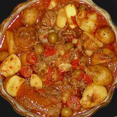 a bowl filled with meat and vegetables on top of a stove burner covered in sauce