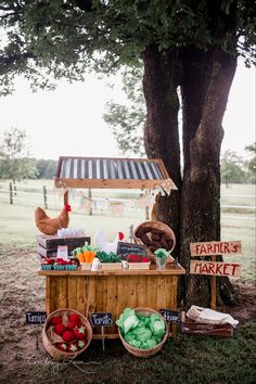 a farmer's market stand in the middle of a field next to a tree