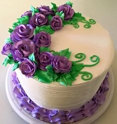 a white cake with purple flowers and green leaves