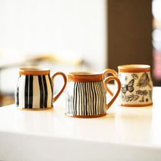 three coffee mugs sitting on top of a white counter