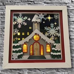 a paper cut christmas scene with a church and snowflakes on the windows,