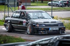 a car that is sitting in the street with some people behind it and another person standing next to it