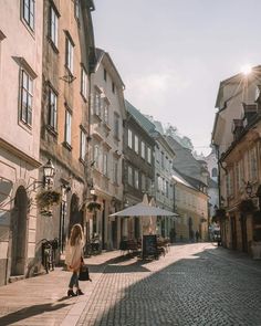 a woman is walking down the street in an old european town with cobblestone streets