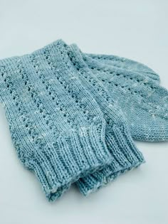 two blue knitted mittens sitting next to each other on top of a white surface