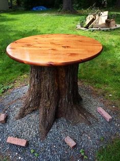 a wooden table sitting on top of a pile of rocks next to a tree stump