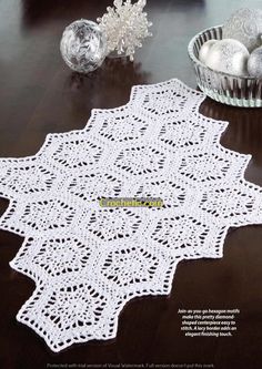 a white doily sitting on top of a wooden table next to silver christmas ornaments