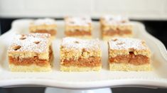 several pieces of dessert sitting on a white platter with powdered sugar toppings