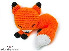 an orange knitted stuffed animal laying on top of it's side with its eyes closed