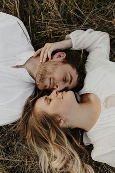 a man and woman laying on the ground together with their eyes close to each other