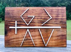 a wooden sign with arrows on it sitting on top of a wood table in front of some trees