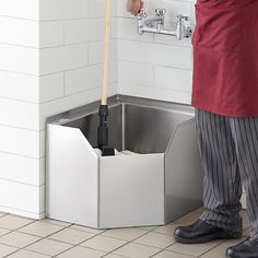 a man standing in front of a sink with an open trash can underneath his arm