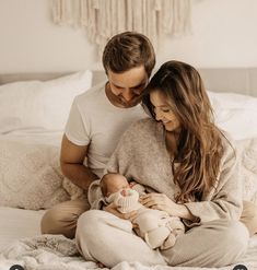 a man and woman sitting on a bed holding a baby