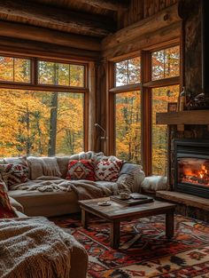 a living room filled with furniture and a fire place next to a large window covered in fall leaves