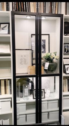 an open book case with many books on the shelves and vases in front of it