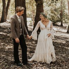 a bride and groom holding hands in the woods