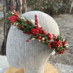 a headpiece with red flowers and greenery on top of a mannequin's head