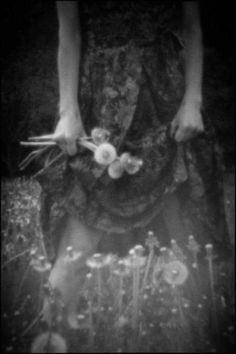 a woman standing in the grass with her hands on her hips and holding flowers around her waist