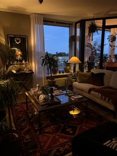 a living room filled with lots of furniture and large windows overlooking the city at night