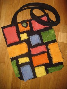 a handbag made out of crayons on the floor with a black strap