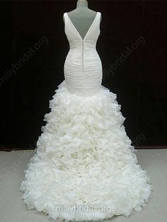 a white wedding dress with ruffles on the bottom and back, in front of a