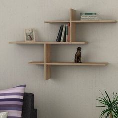 three wooden shelves on the wall above a couch with pillows and a potted plant