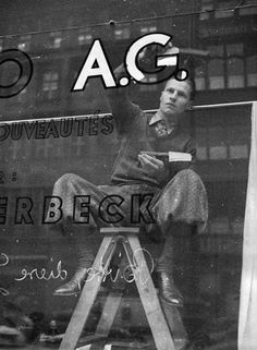 a man sitting on top of a ladder in front of a store window with the words ac