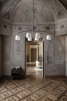 an open door leading to a hallway with chandelier and lamps on the ceiling