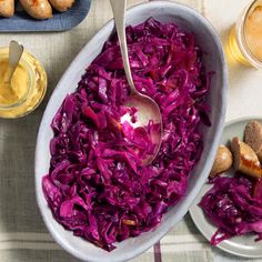 a bowl filled with red cabbage next to two plates of potatoes and dipping sauces