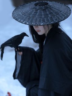 a woman with a black hat holding a bird