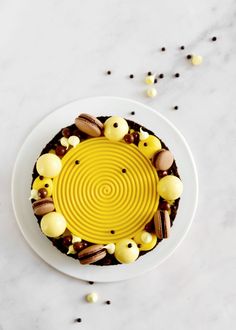 a white plate topped with a cake covered in yellow frosting and chocolate candies